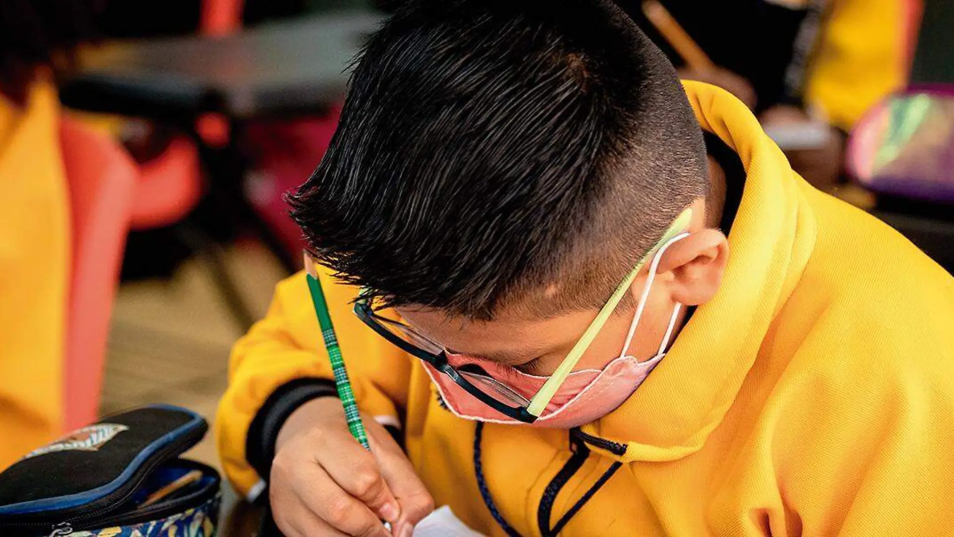 Niño tomando apuntes en el salón de clases